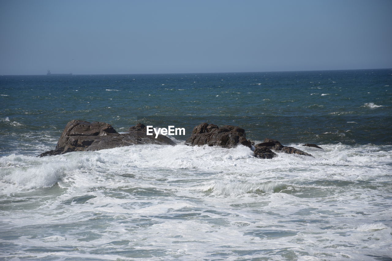 SEA WAVES SPLASHING AGAINST CLEAR SKY