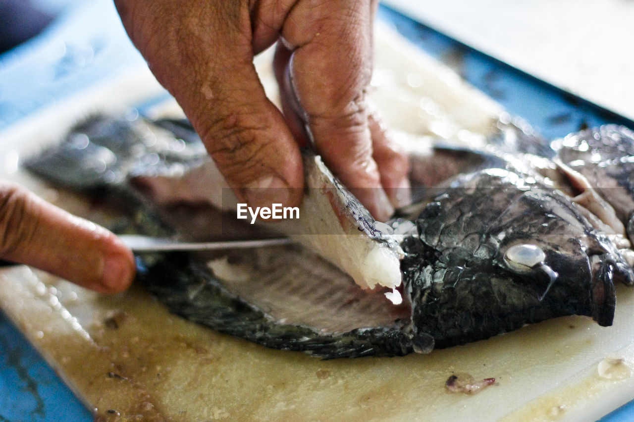 Cropped image of hands filleting fish at market