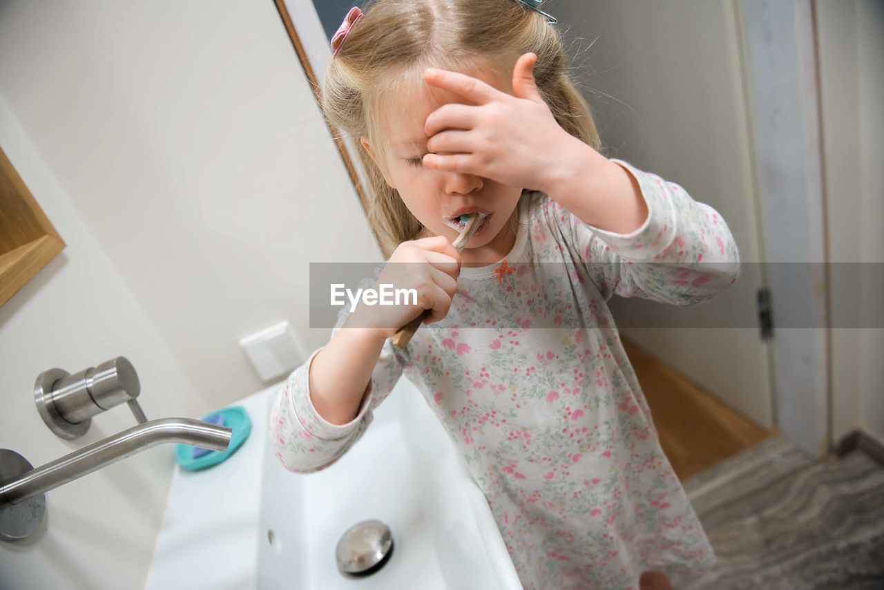 Girl brushing teeth in bathroom at home