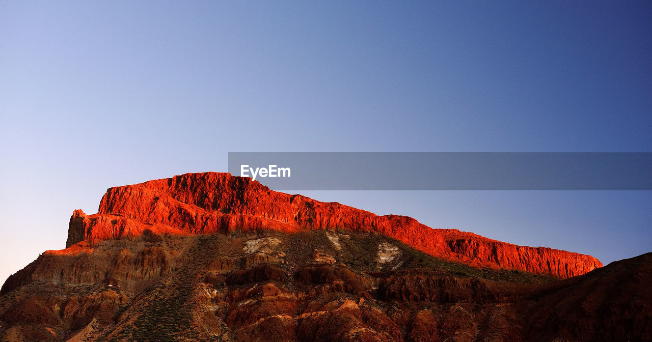 Low angle view of rocky mountains at el teide national park against clear blue sky