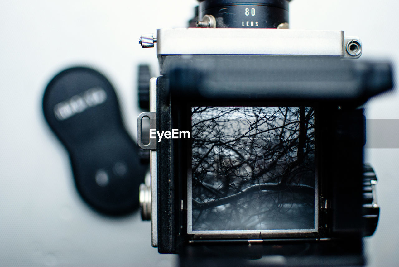 Close-up of vintage camera photographing bare trees during winter