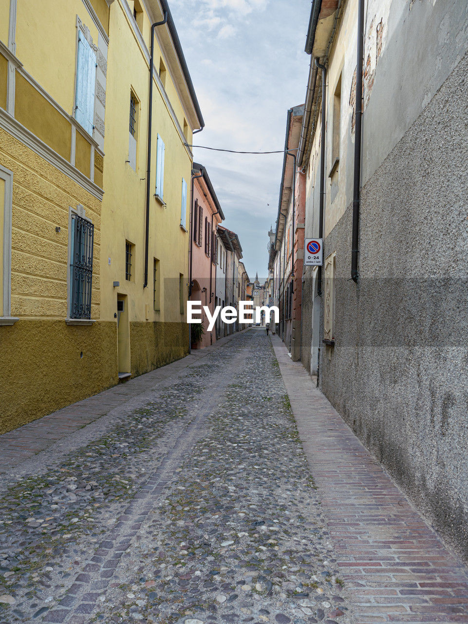 architecture, road, street, building exterior, alley, lane, built structure, city, building, neighbourhood, infrastructure, road surface, wall, the way forward, town, cobblestone, urban area, residential district, diminishing perspective, sky, footpath, nature, no people, day, house, outdoors, cloud, narrow, residential area, vanishing point, wall - building feature, transportation