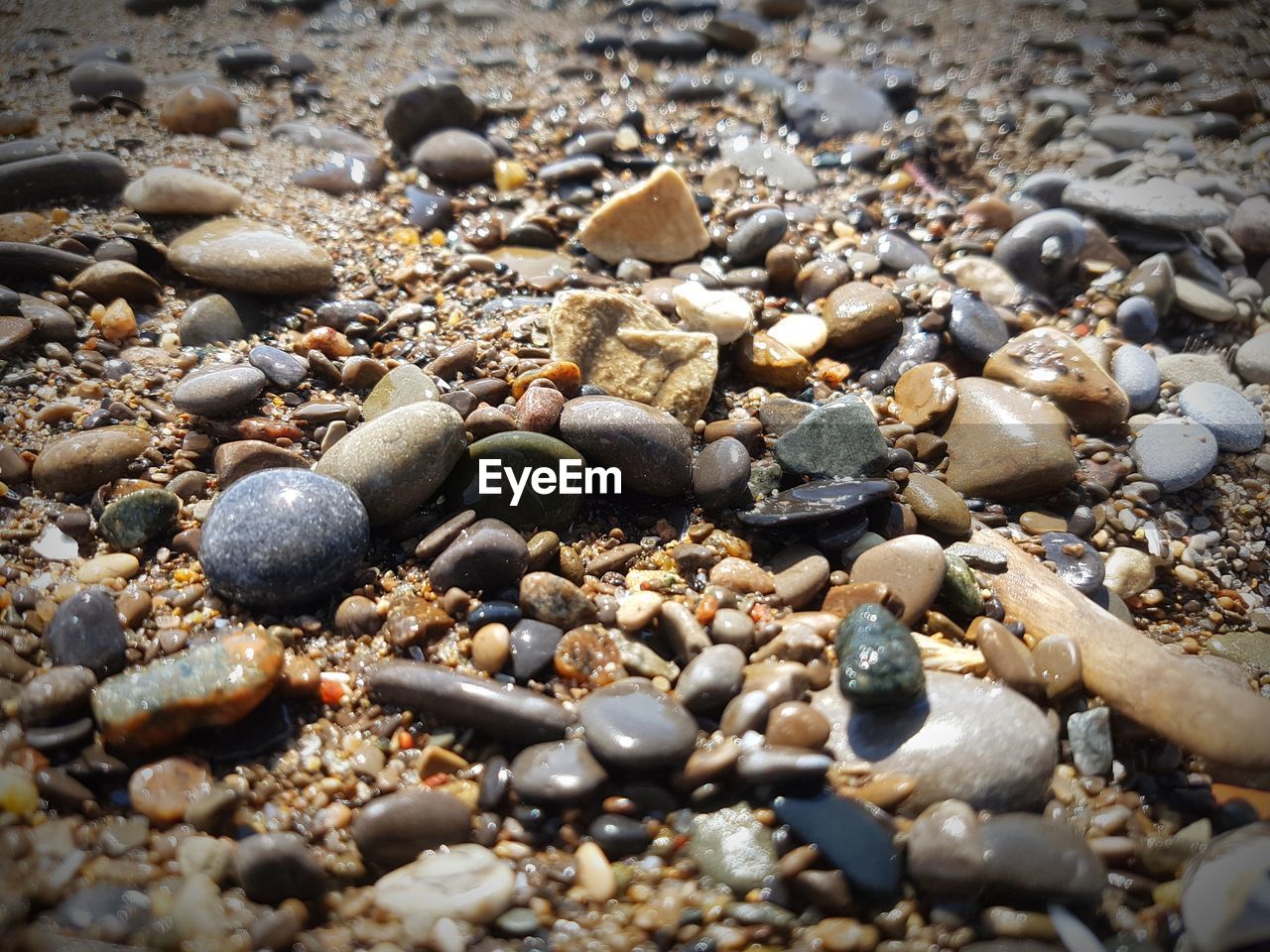 HIGH ANGLE VIEW OF PEBBLES ON BEACH