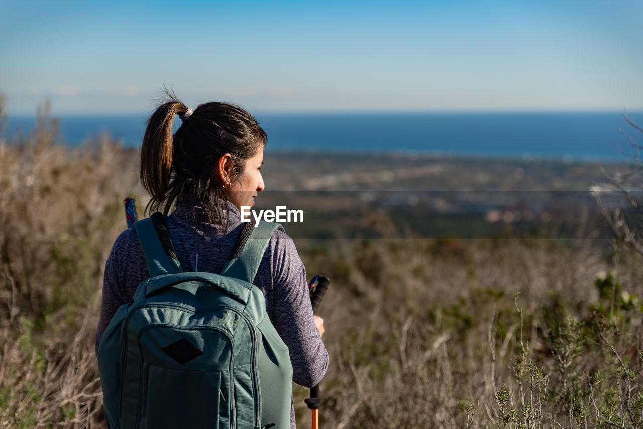 Woman contemplates the landscapes of the garraf natural park while walking the paths of a mountain.