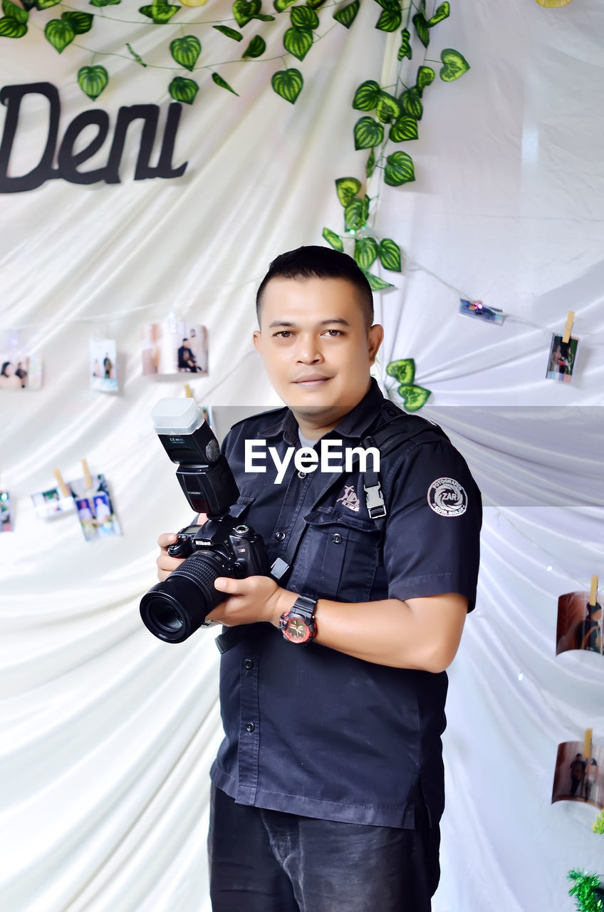 Portrait of young man holding camera