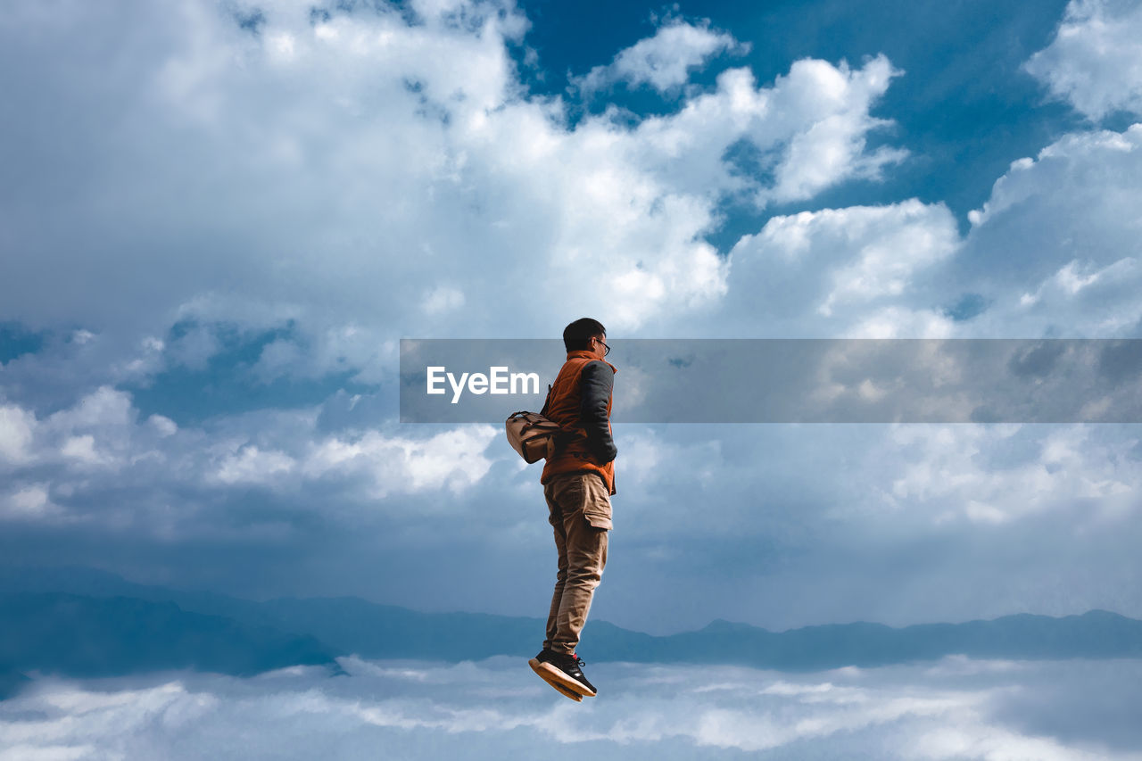 Low angle view of man jumping against sky