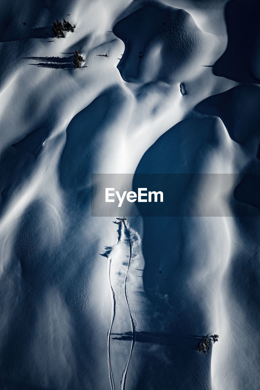 Aerial photo of two adults backcountry powder skiing in the kootenays, b.c., canada
