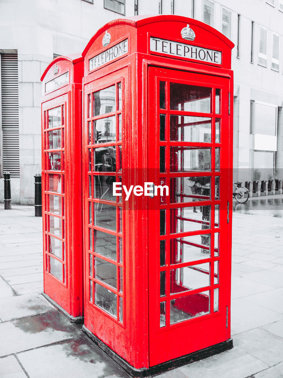 RED TELEPHONE BOOTH ON SIDEWALK AGAINST CITY