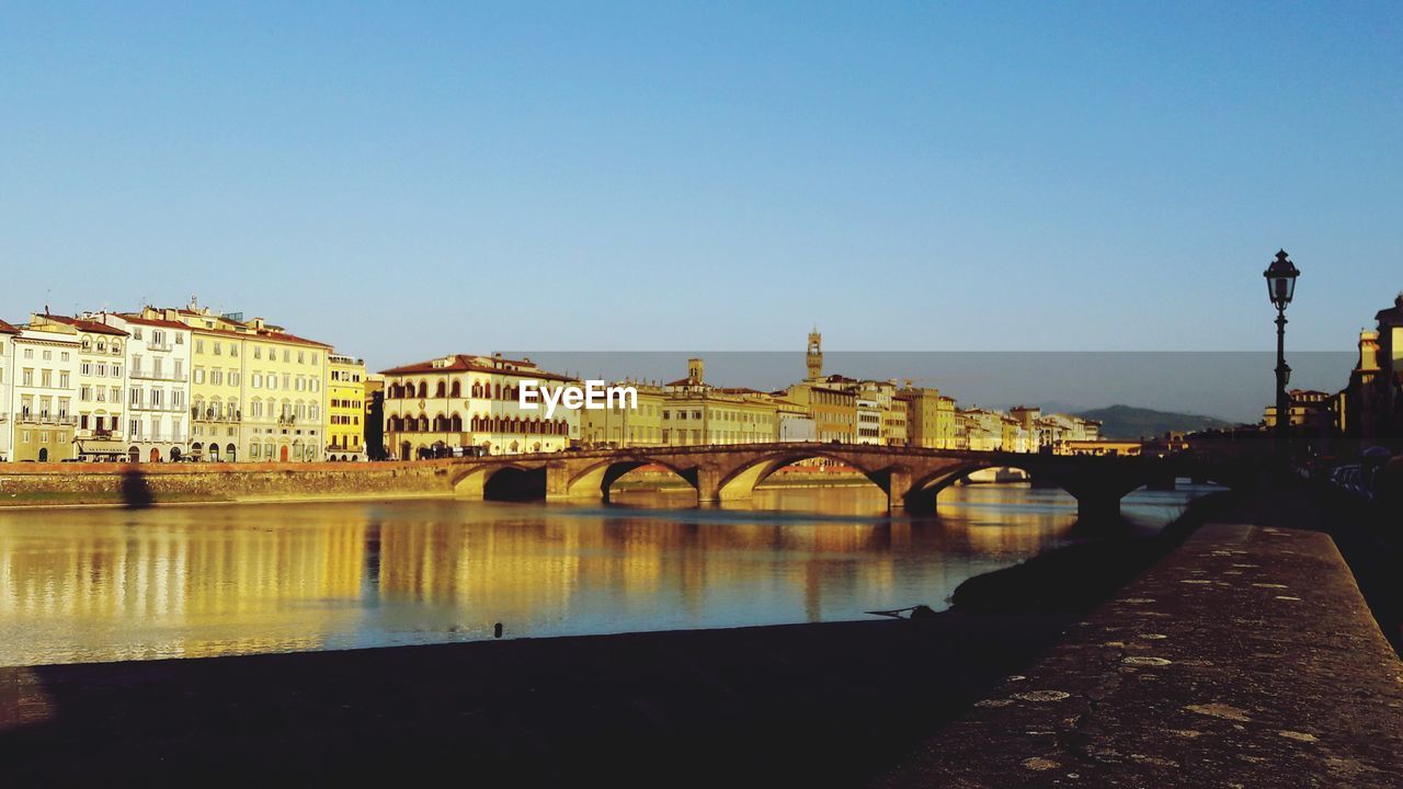 Arch bridge over river against blue sky