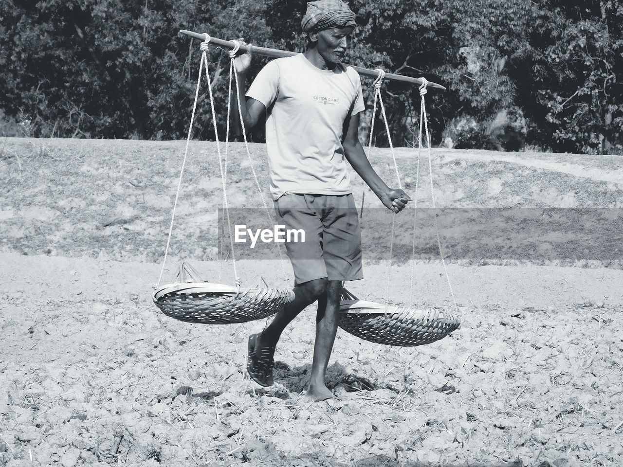 Man carrying wicker baskets on field