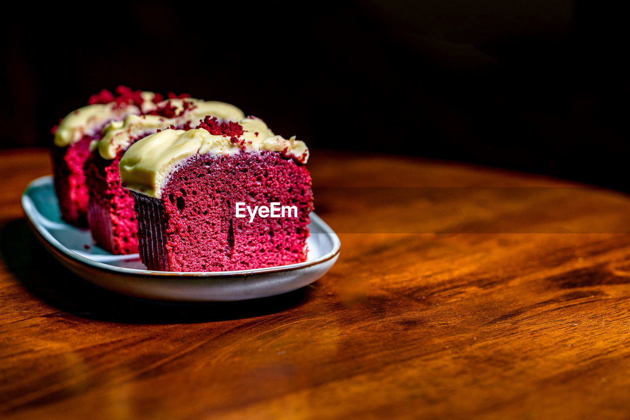 Slices of red velvet cake in a plate on wooden table