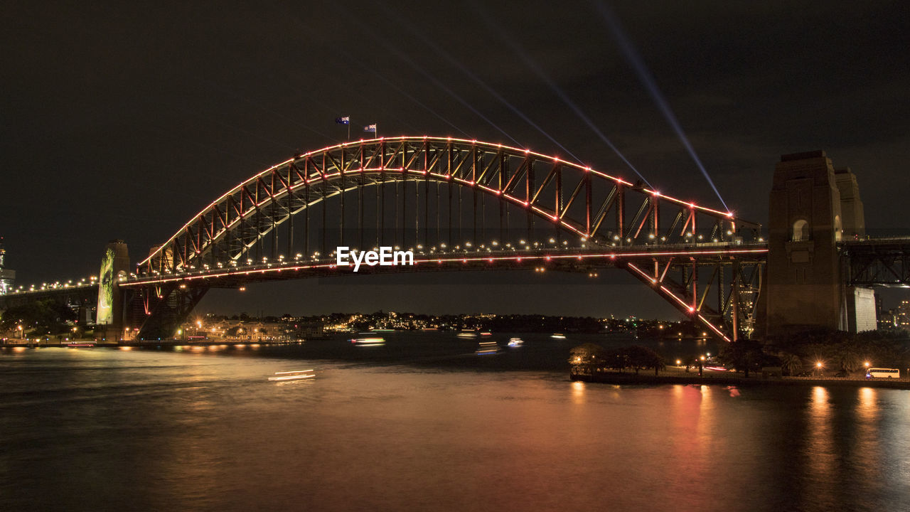 Illuminated bridge over river at night