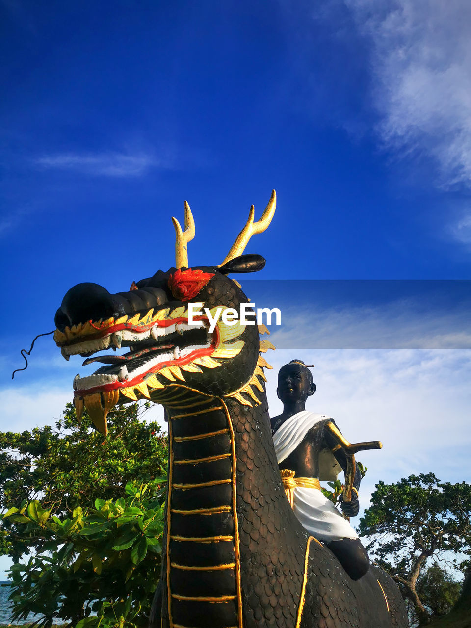 Low angle view of buddhist statue against blue sky