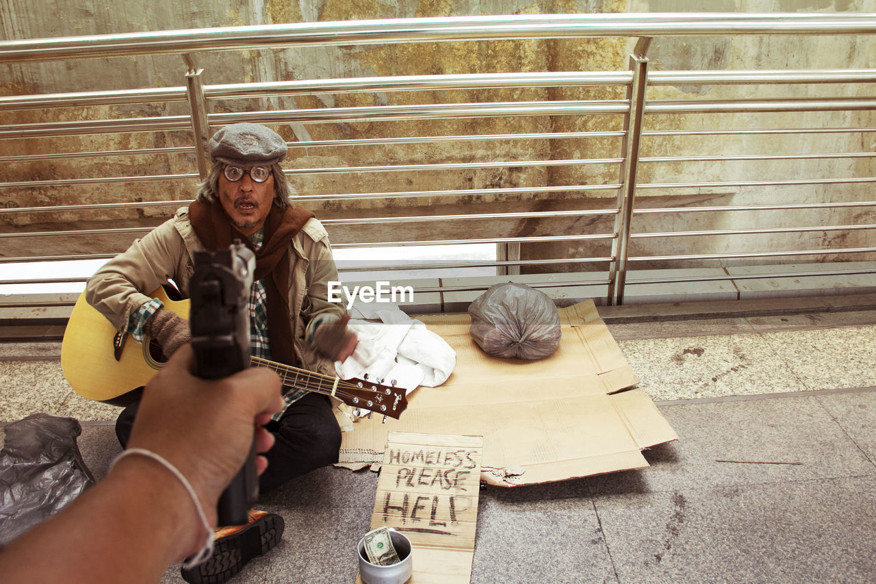 Cropped image of criminal shooting beggar