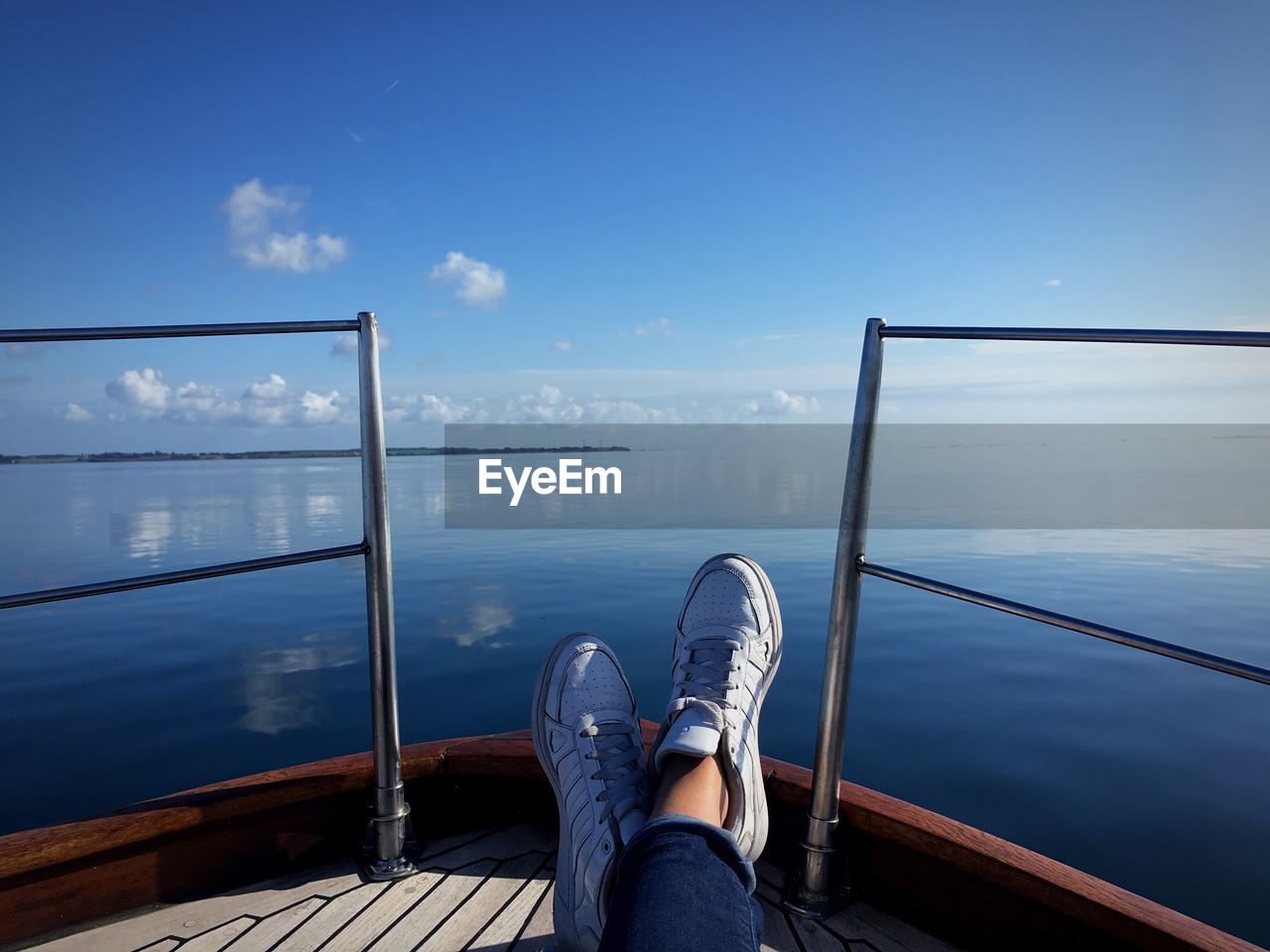 Low section of woman resting on boat by sea against sky