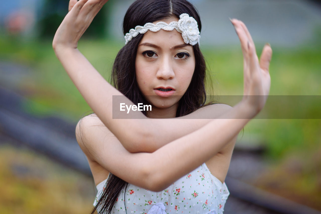 PORTRAIT OF BEAUTIFUL YOUNG WOMAN WITH ARMS RAISED