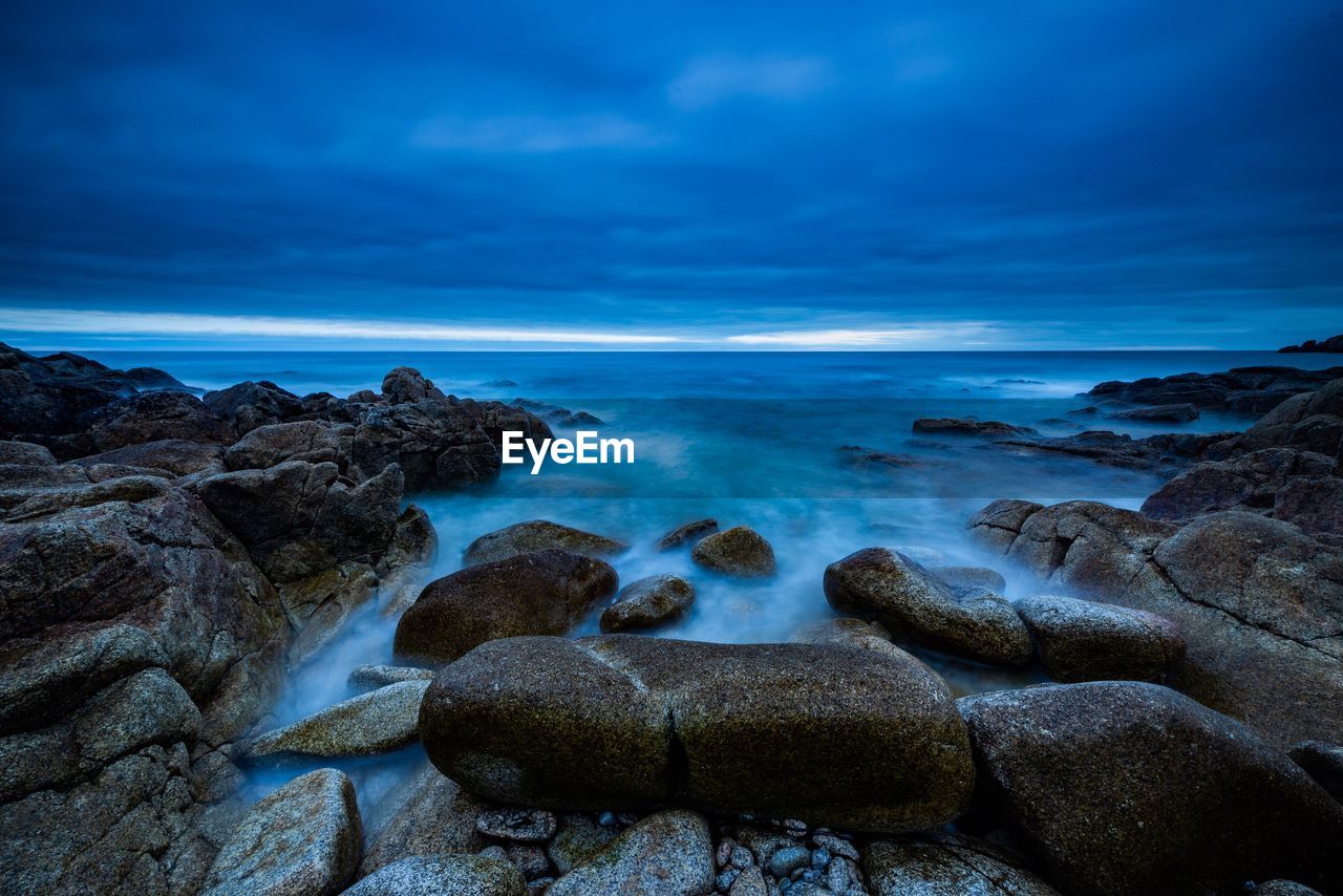 Rocks on sea shore against sky