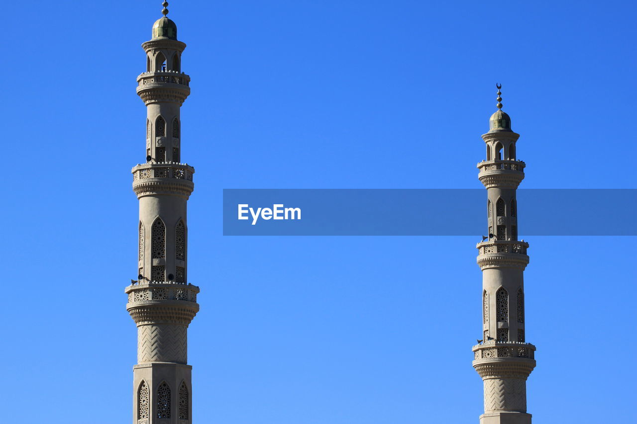 Low angle view of towers against clear blue sky