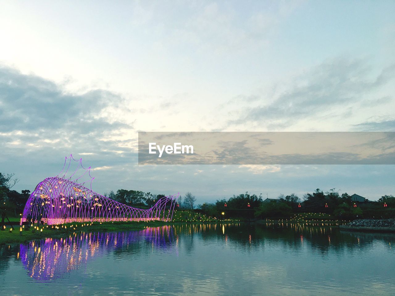 ILLUMINATED BUILT STRUCTURE IN LAKE AGAINST SKY