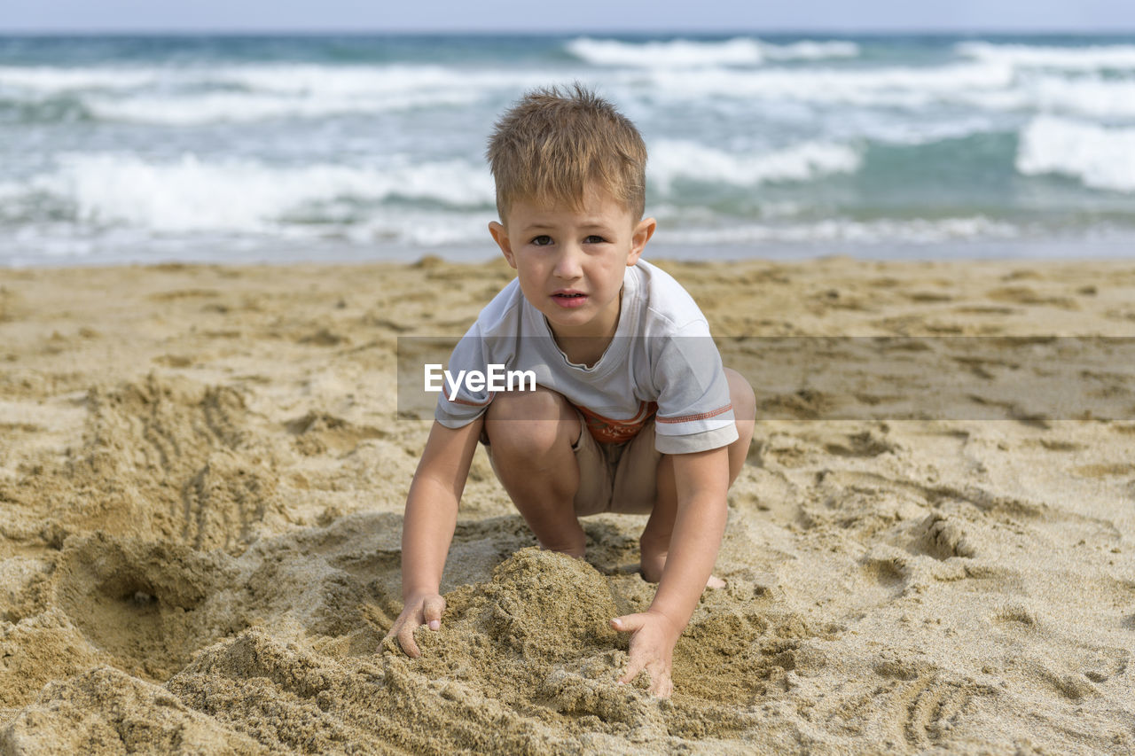 Full length of boy playing on beach against sky