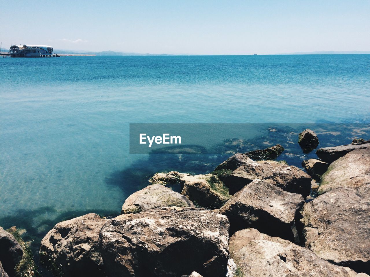 Rocks at beach against clear sky