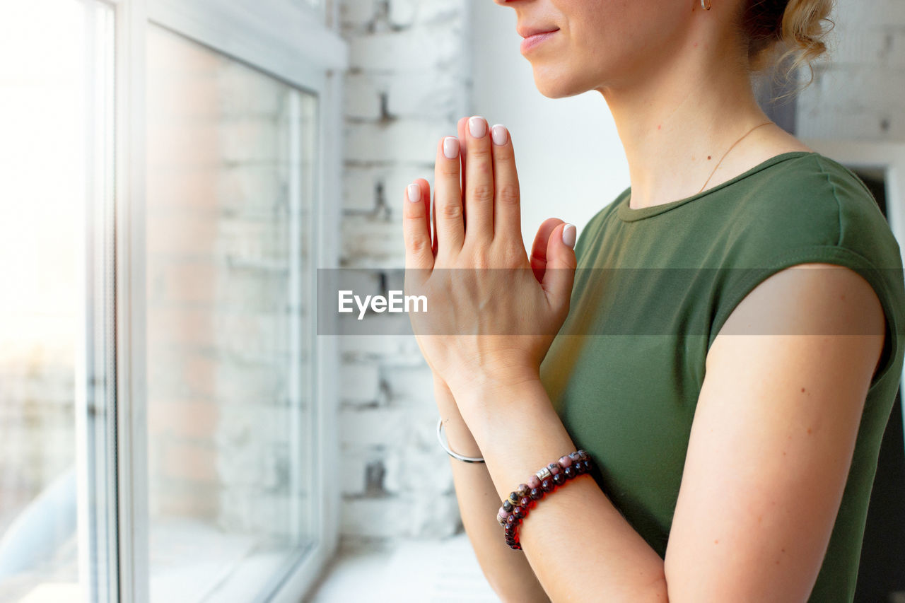 Girls in a green t-shirt, in a yoga pose close-up, folded their palms together on their chest