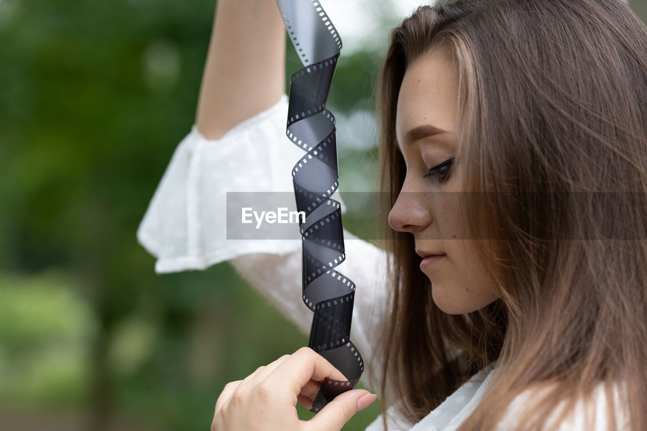 Close-up of young woman holding film reel outdoors