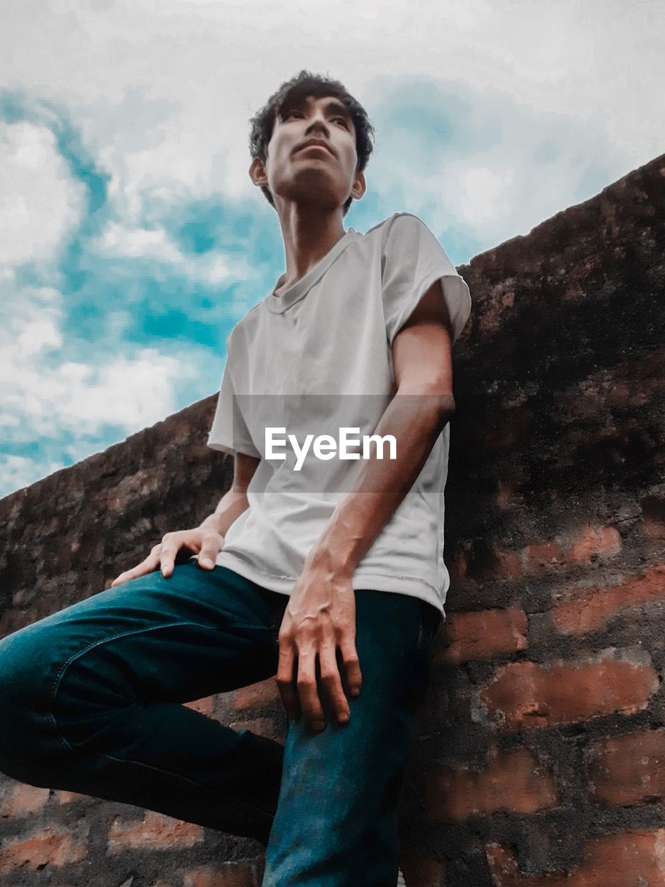 Low angle view of young man looking away against wall