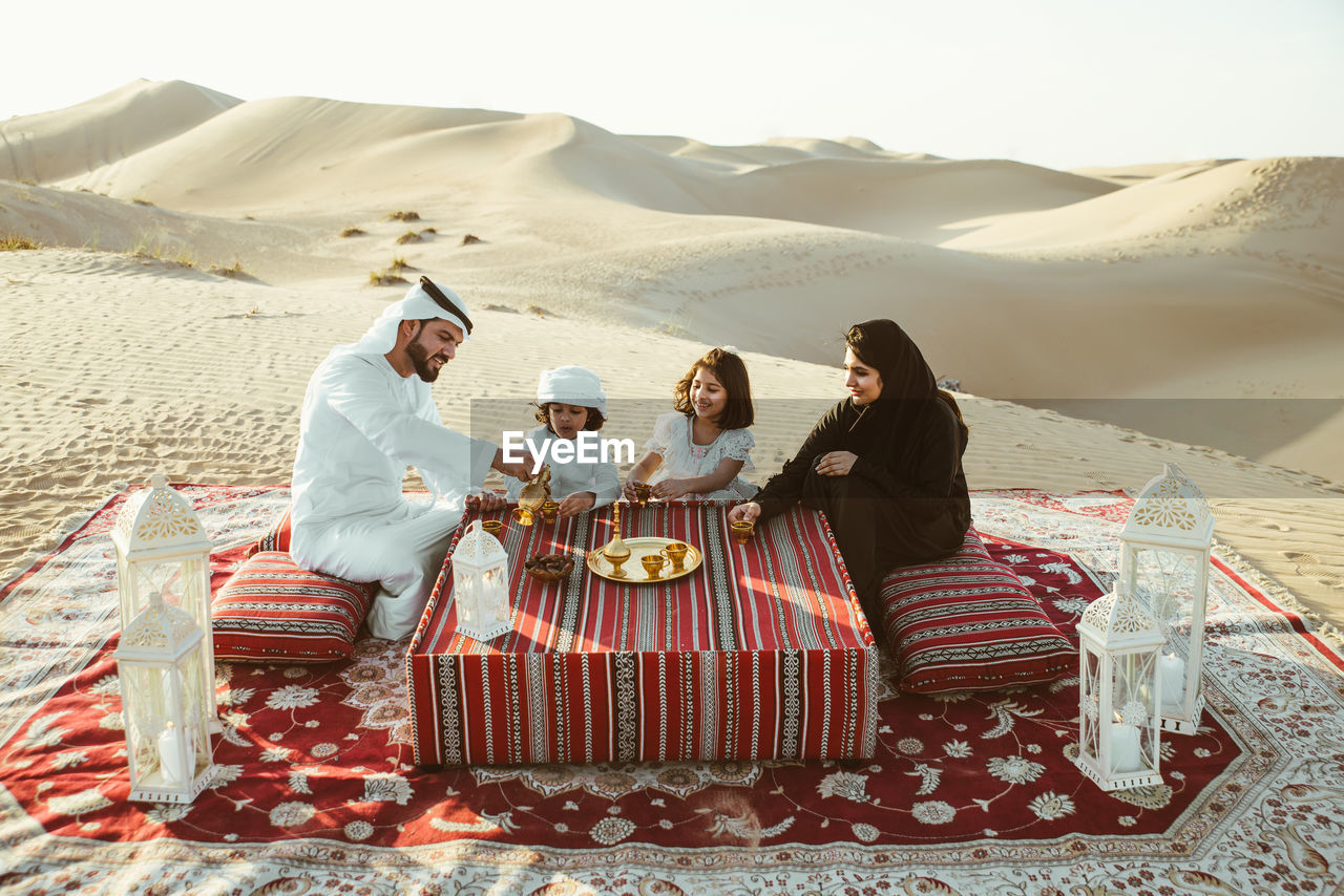 High angle view of family having tea on carpet at desert