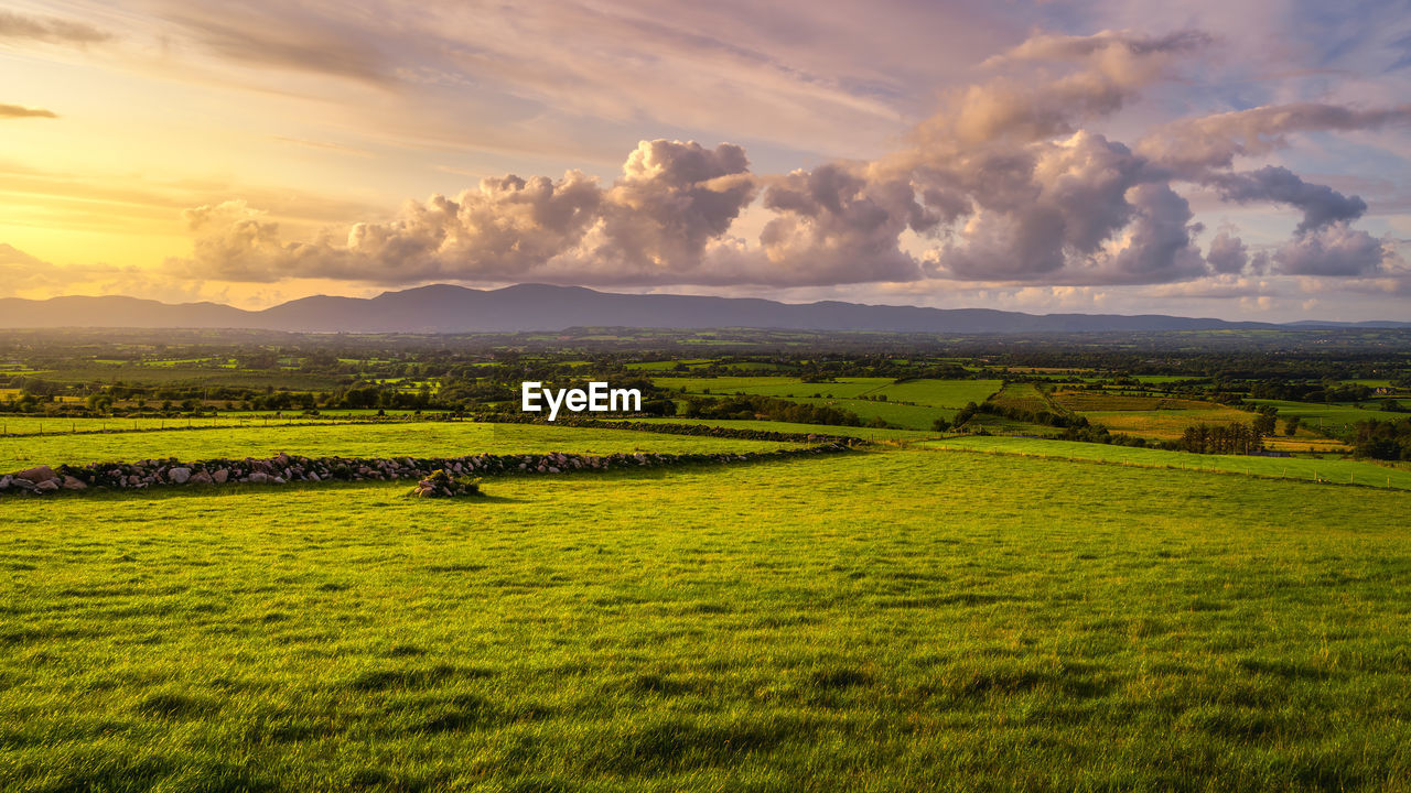 Beautiful sunset at golden hour over green fields and farms, macgillycuddys reeks mountains, ireland