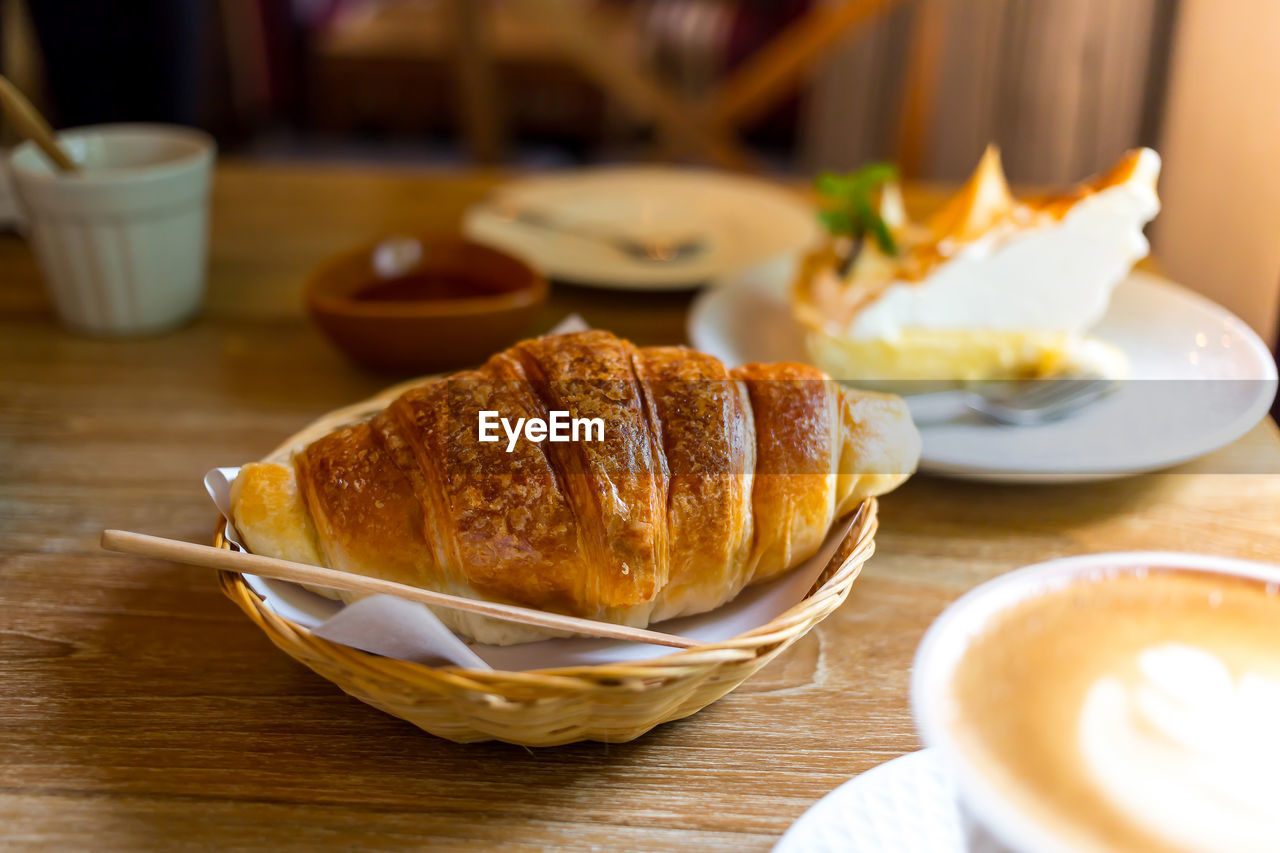Close-up of croissant with coffee cup on table