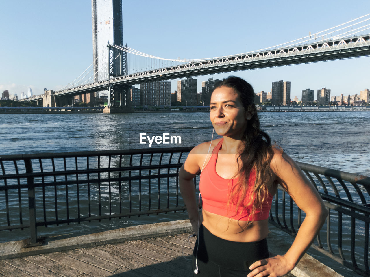 Young woman exercising on footpath against bridge in city