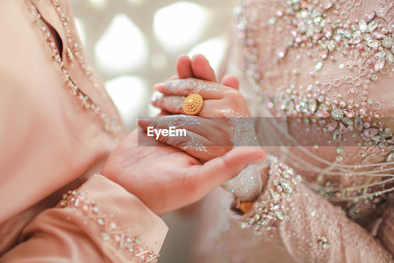 Midsection of bridegroom holding hands during wedding ceremony