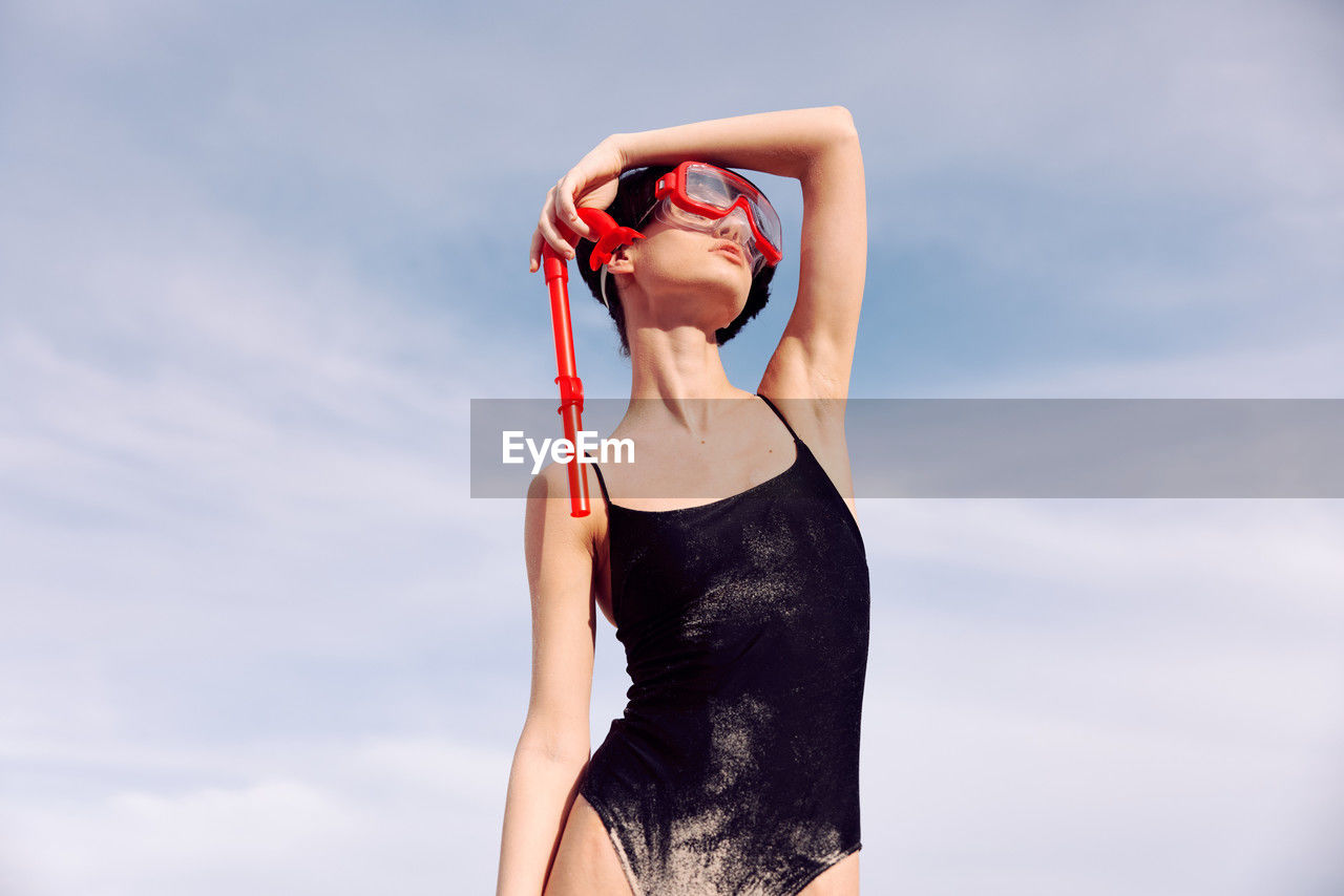 midsection of woman with arms raised against sky