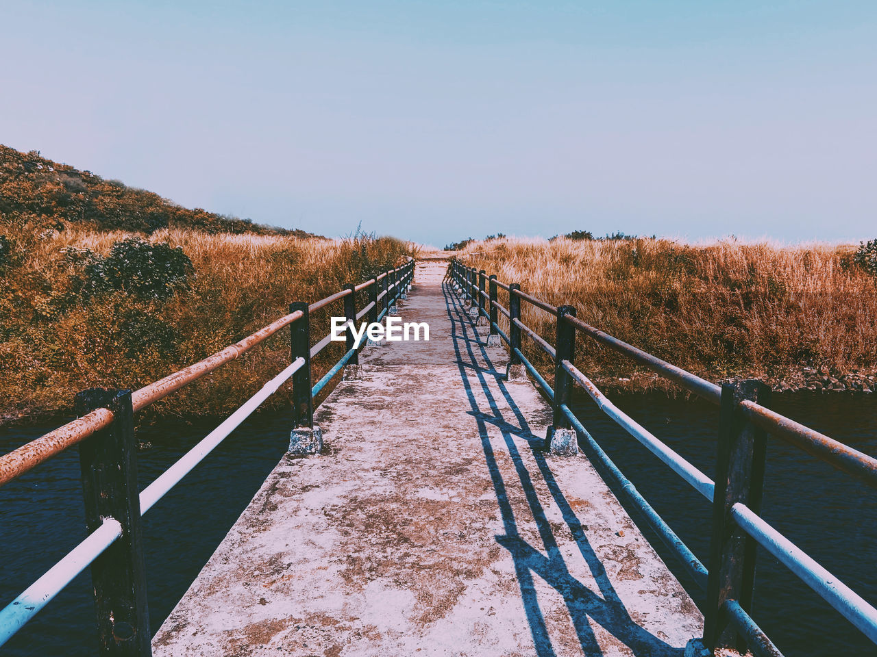 Footbridge over landscape against clear sky