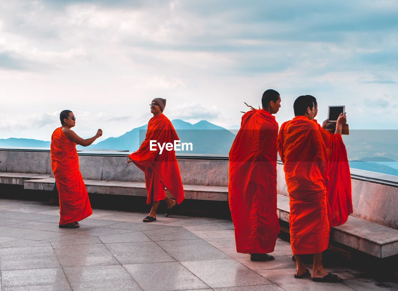 REAR VIEW OF FRIENDS STANDING BY TEMPLE AGAINST SKY