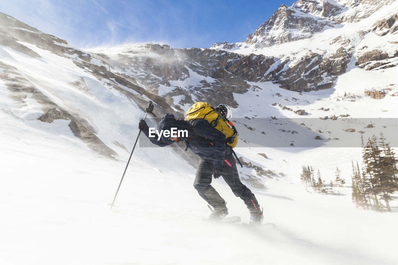 Hiker battles wind above black lake, rocky mountain national park