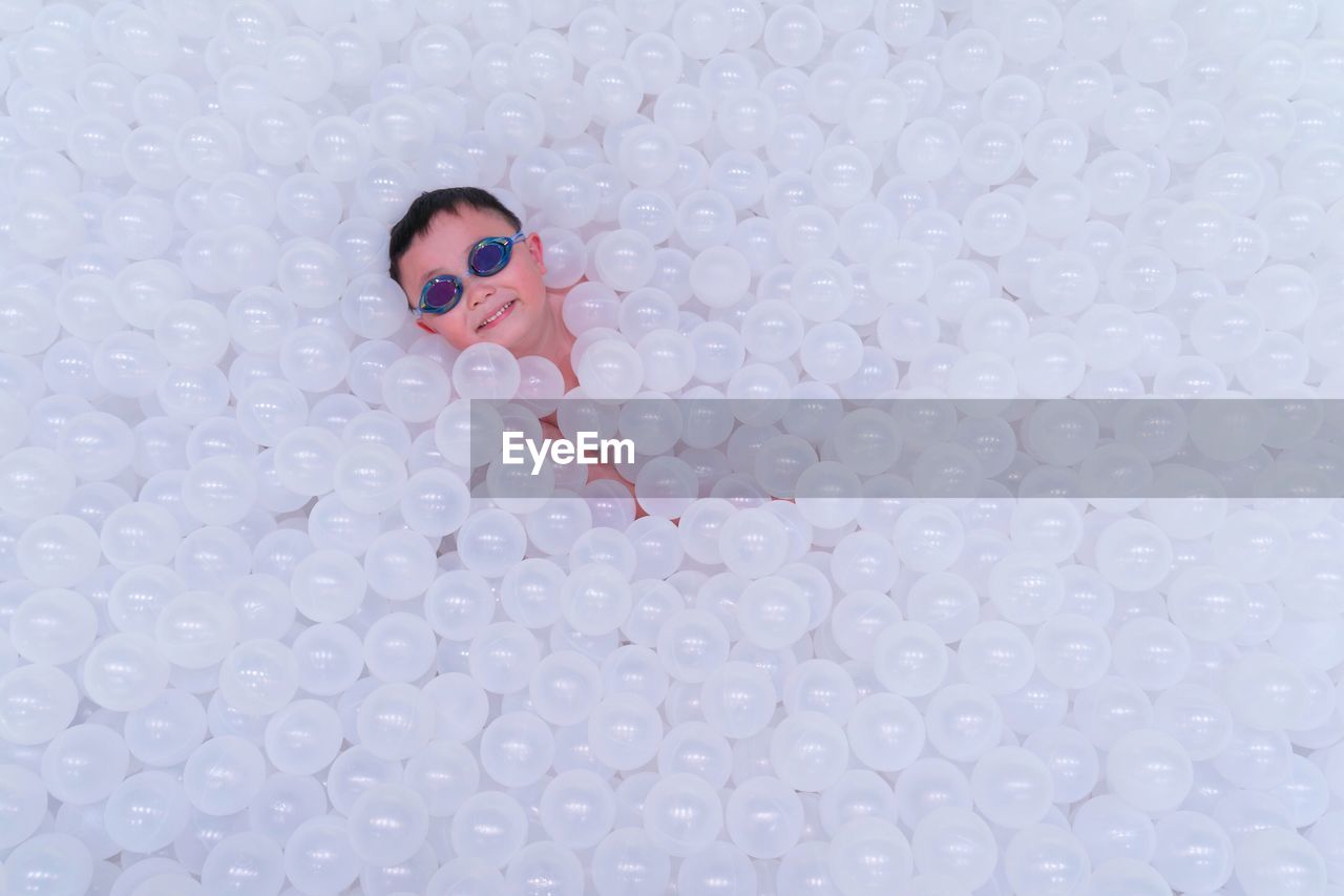 High angle view of boy lying with white balls