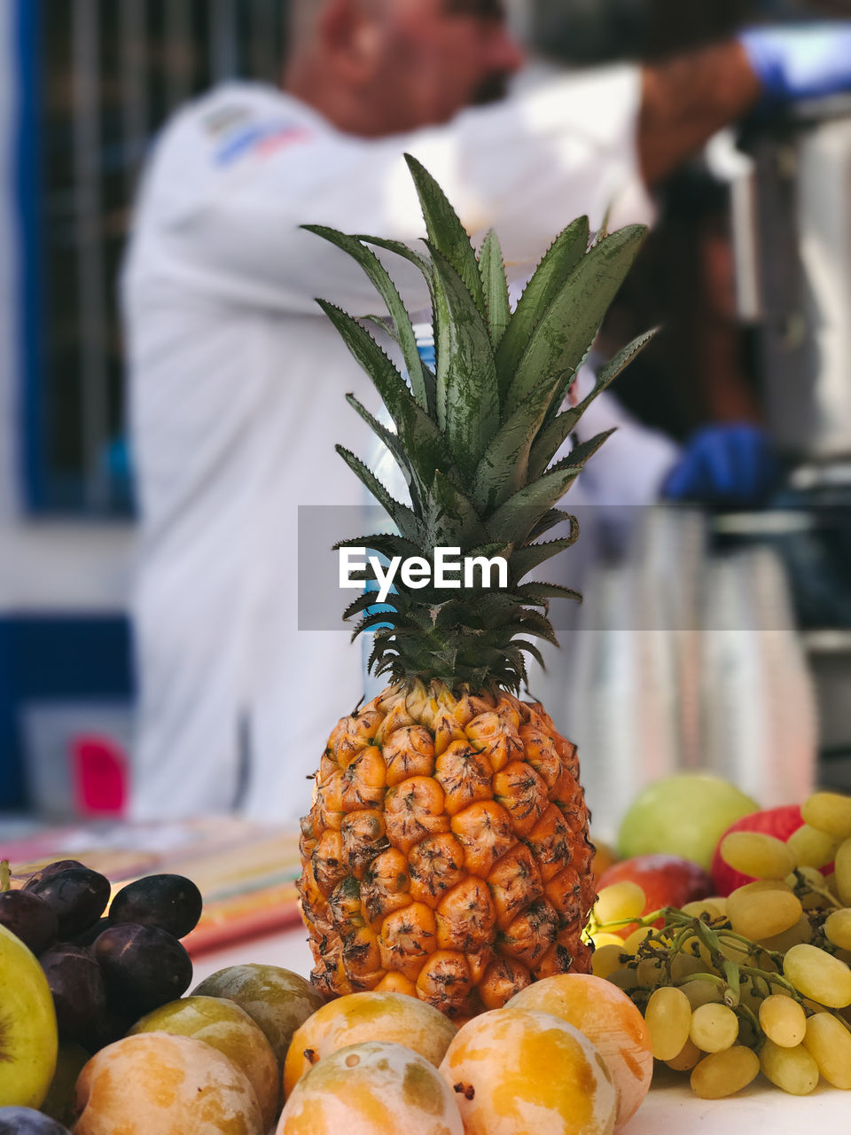 Close-up of fruits on table with man standing in background