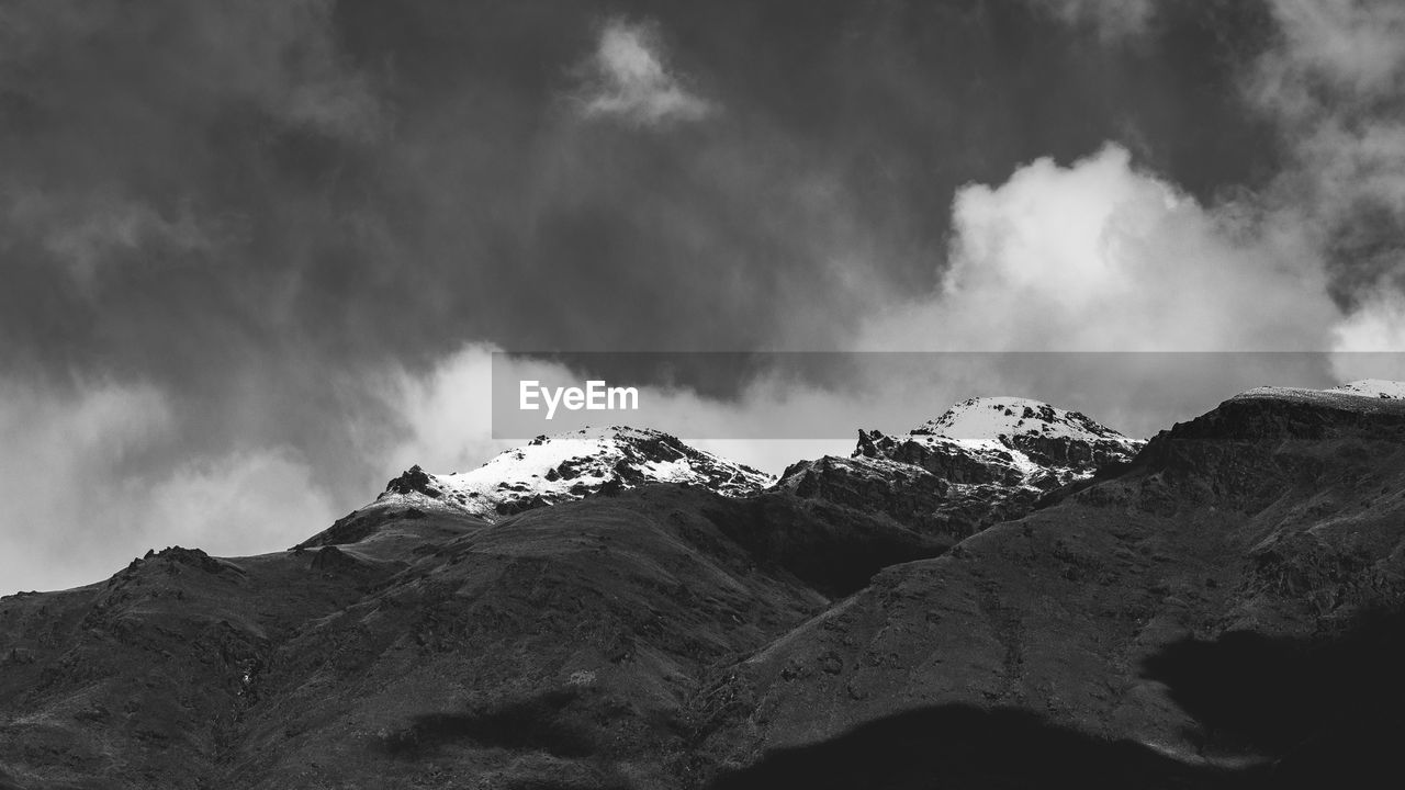 mountain, cloud, snow, sky, environment, scenics - nature, black and white, beauty in nature, landscape, monochrome, mountain range, monochrome photography, nature, darkness, cold temperature, no people, winter, snowcapped mountain, mountain peak, land, travel destinations, outdoors, non-urban scene, travel, dramatic sky, rock, storm, extreme terrain, tranquility