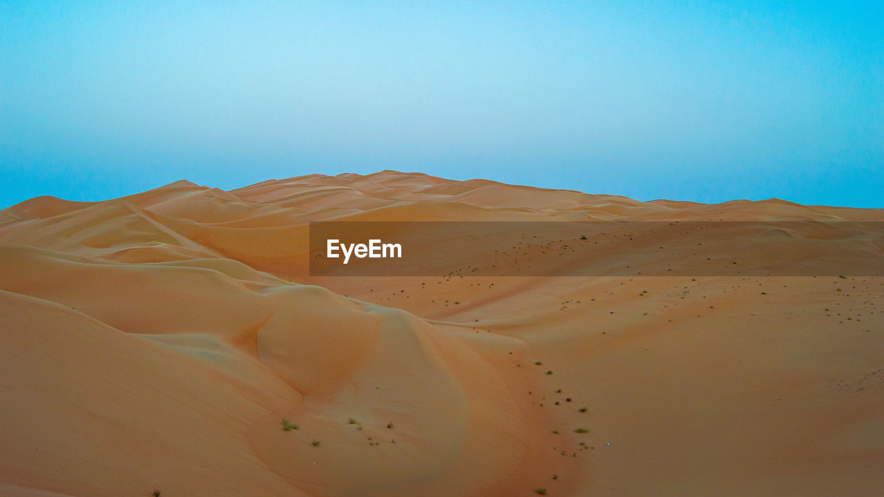 Scenic view of desert against clear blue sky