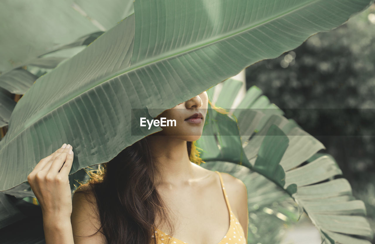 Portrait of young woman standing amidst plants