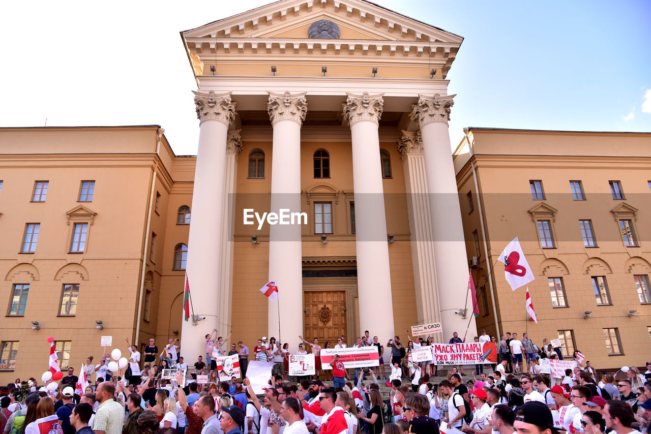 PEOPLE IN FRONT OF BUILDING AGAINST SKY