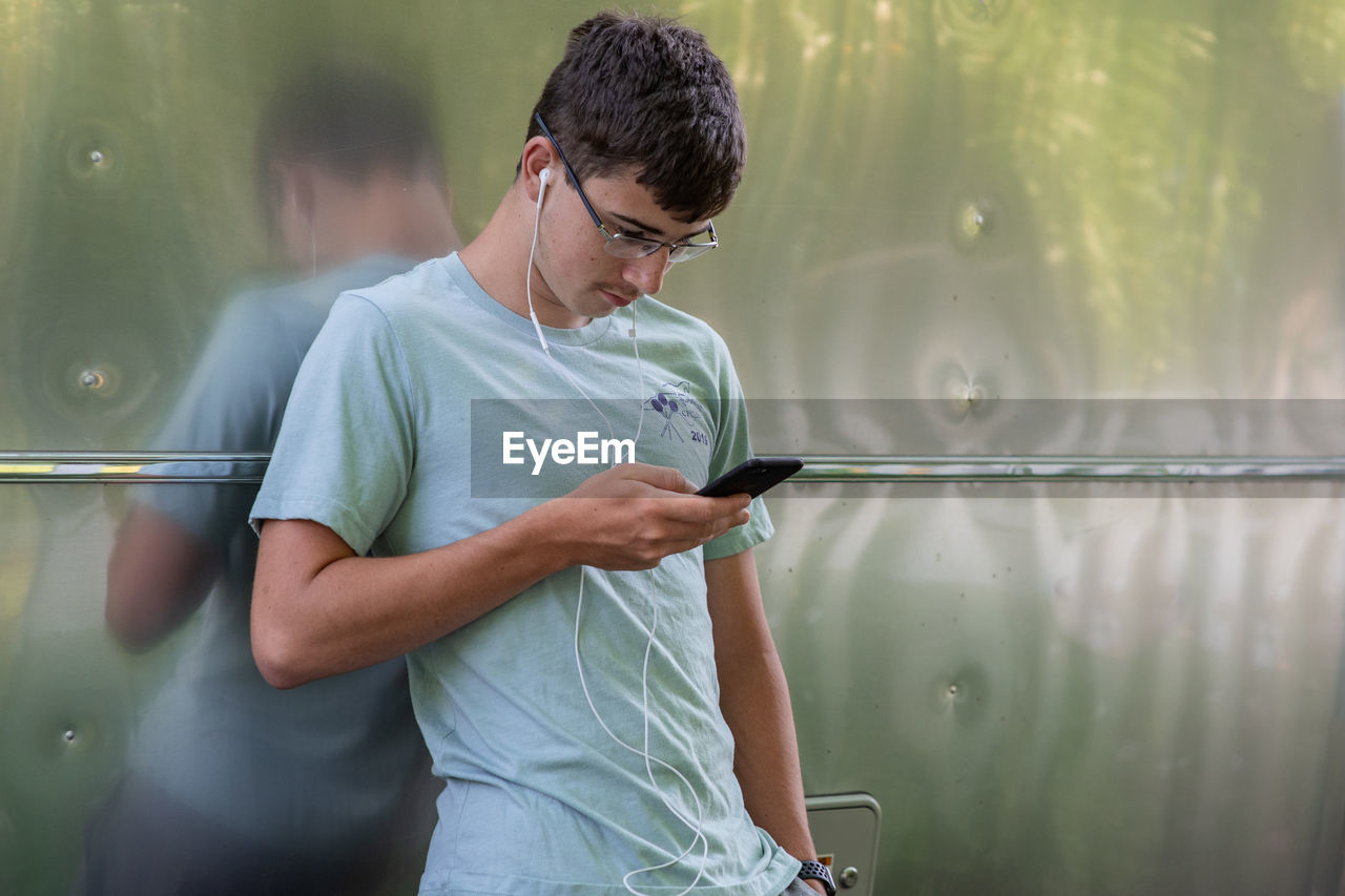 YOUNG MAN USING MOBILE PHONE WHILE PHOTOGRAPHING