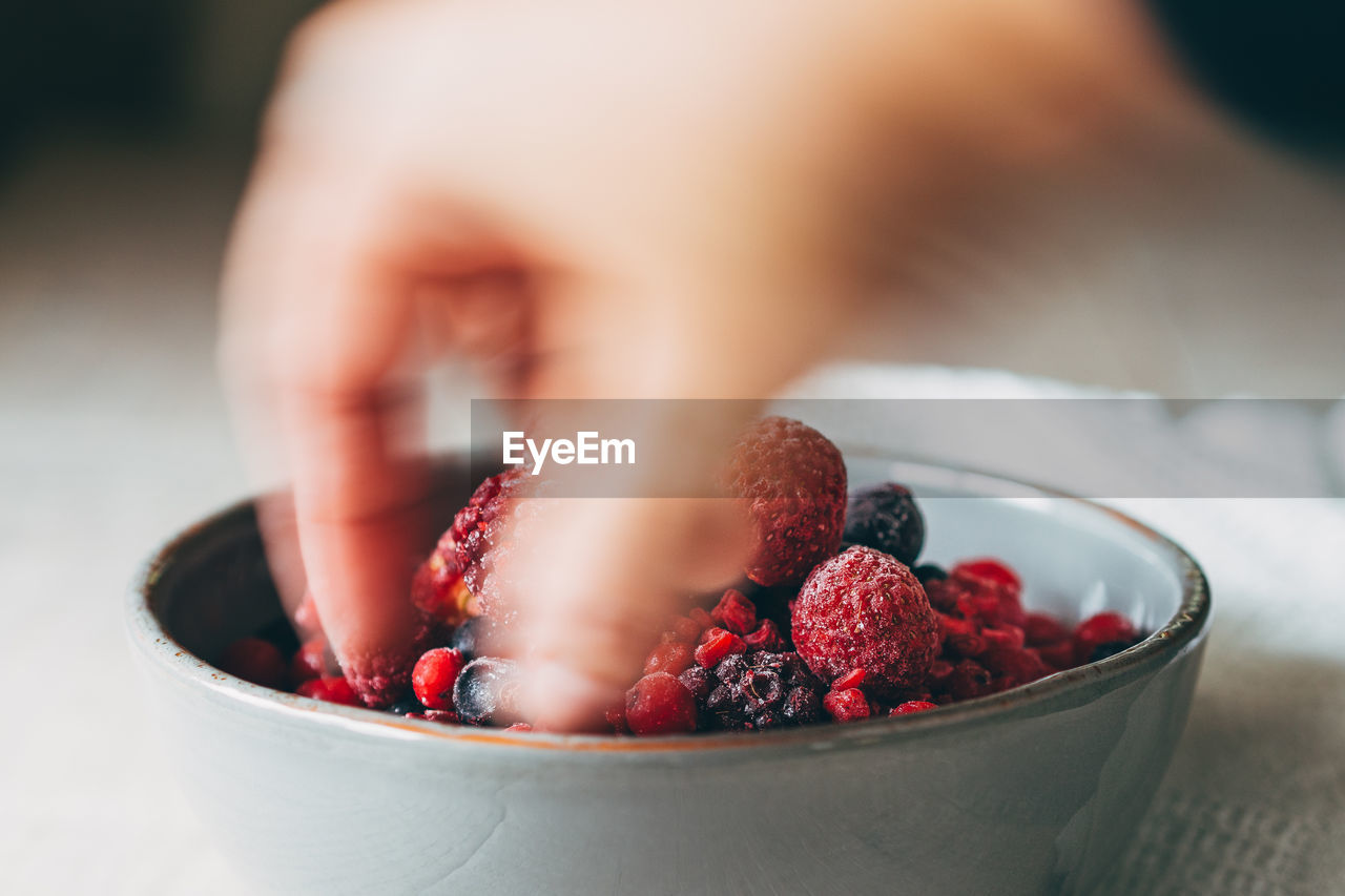 Blurred motion of hand taking berries from bowl