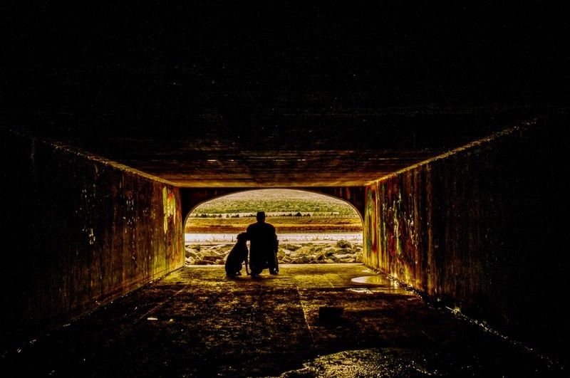 REAR VIEW OF WOMAN WALKING IN TUNNEL