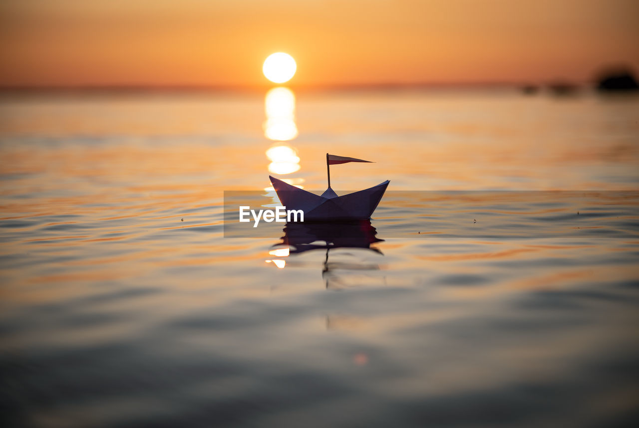 PAPER FLOATING ON WATER AT SUNSET