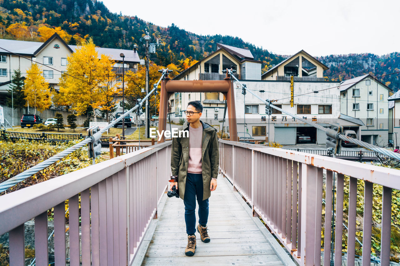 Full length of man walking on bridge against buildings