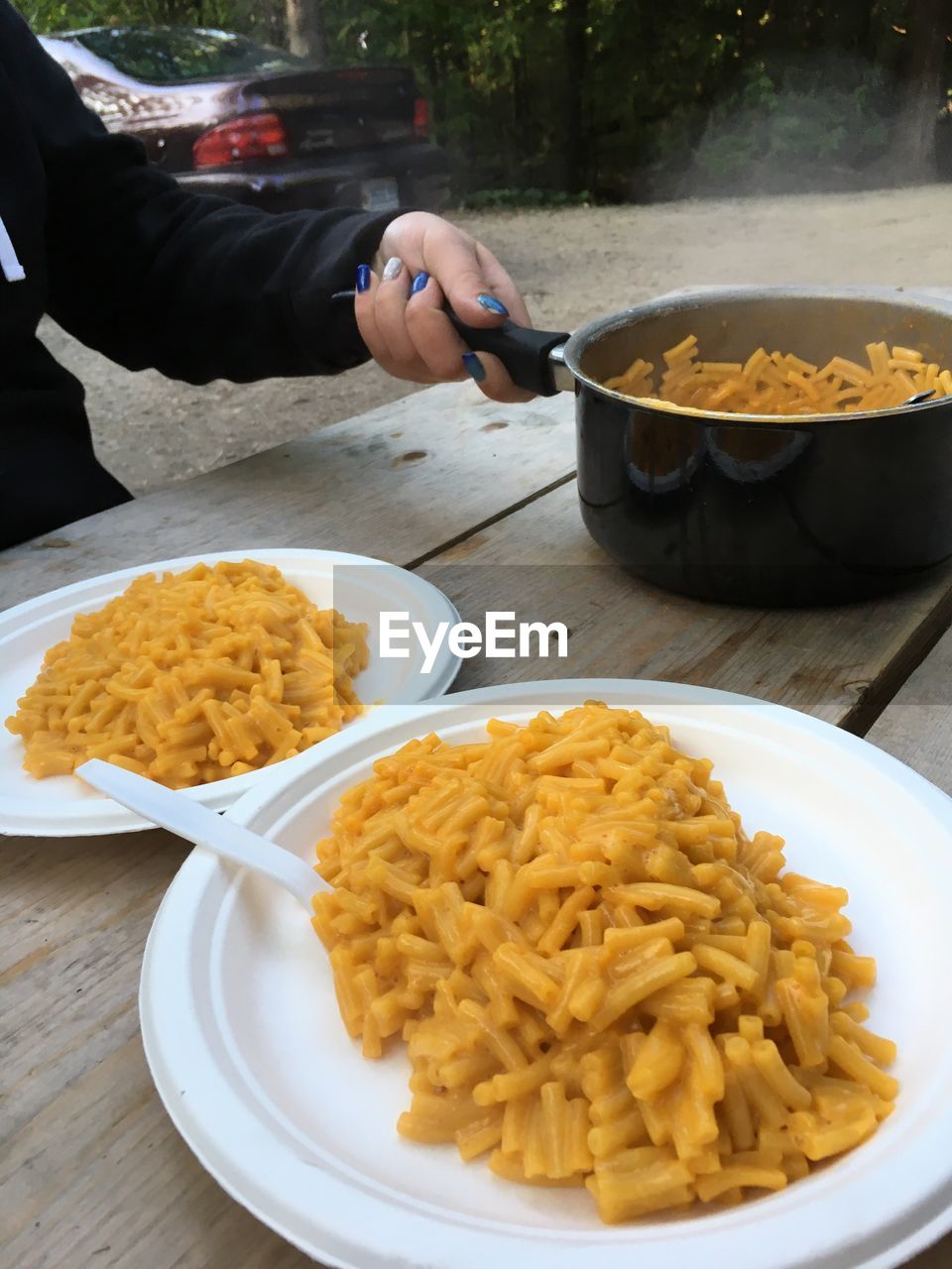 CLOSE-UP OF HAND HOLDING FOOD IN PLATE ON TABLE