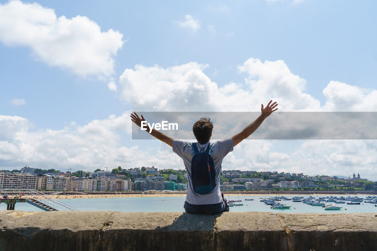 rear view of woman doing yoga on beach against sky